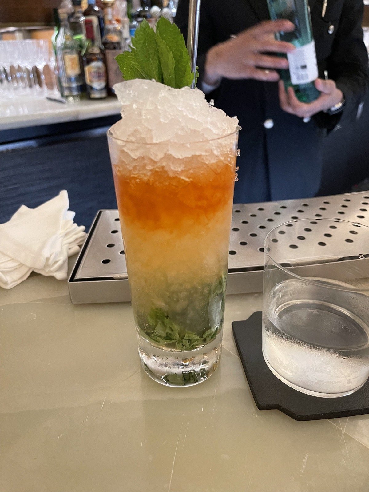 Layered cocktail topped with crushed ice and a green garnish at Claridge’s